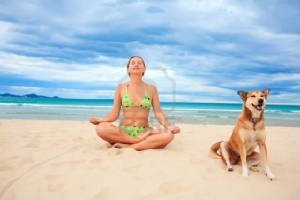 5508110-mujer-con-perro-est-meditando-en-la-playa-tropical.jpg